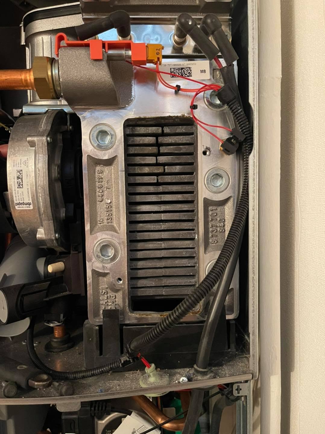 A boiler opened up with the burner and fan assembly exposed